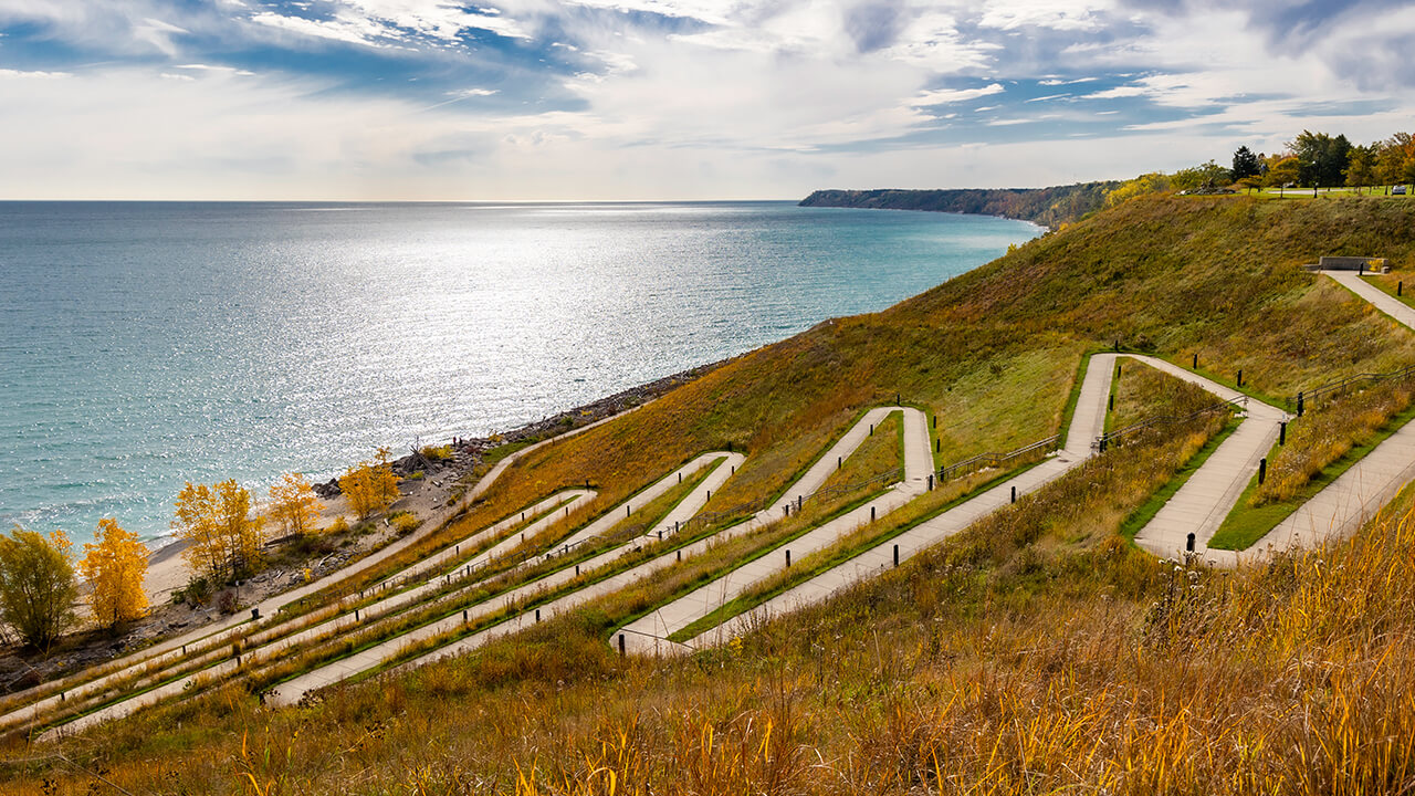 A beautiful view of Lake Michigan right from the top of Concordia’s bluff, in view of a sidewalk leading down to the lake, zigzagging back and forth at a slight slope to the beach.