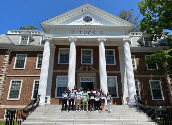 Student group photo with completion awards at Tuck building